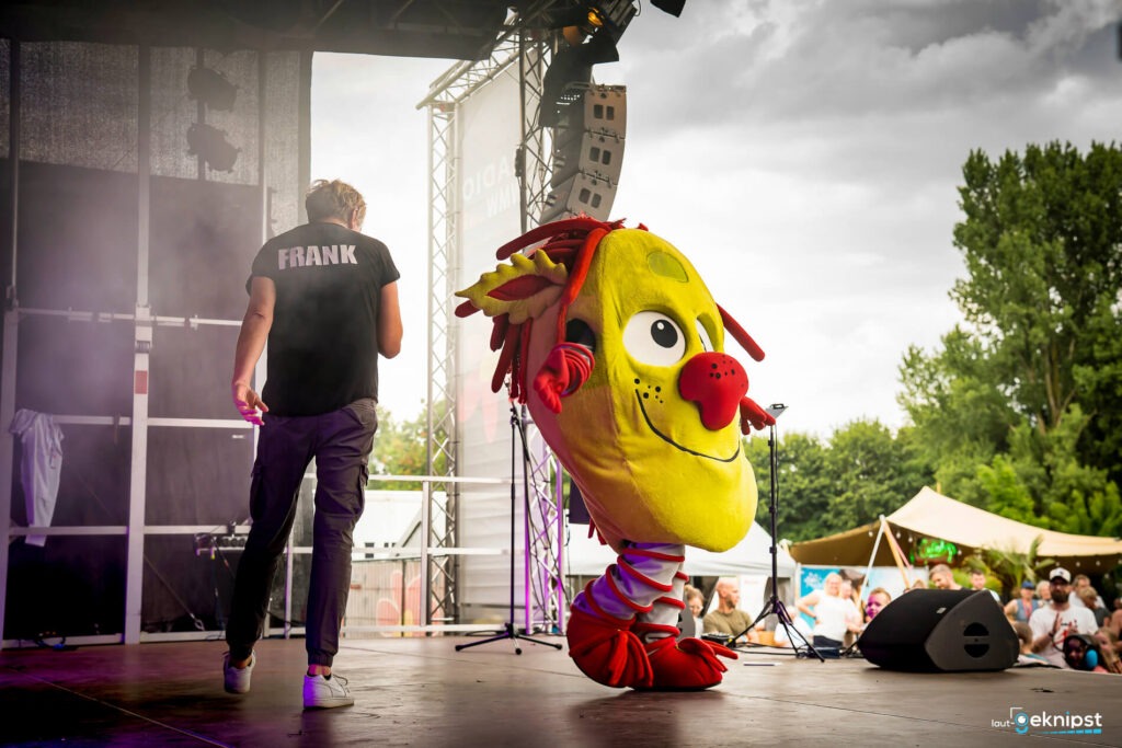 Mann und gelbes Maskottchen auf Bühne bei Event.