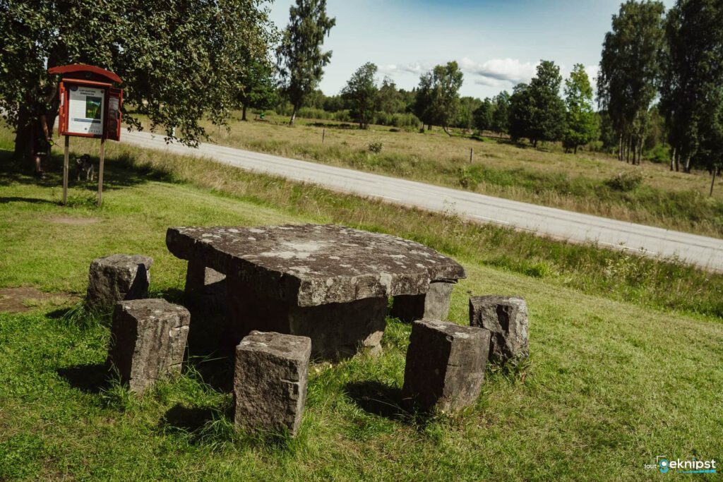 Megalithtisch auf grüner Wiese neben Straße.