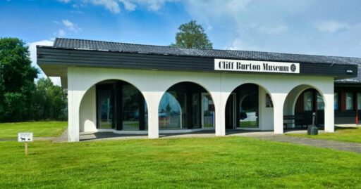 Museum mit gewölbtem Eingang und Rasen.