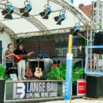 Live-Musik auf einer Außenbühne mit Leinwand.