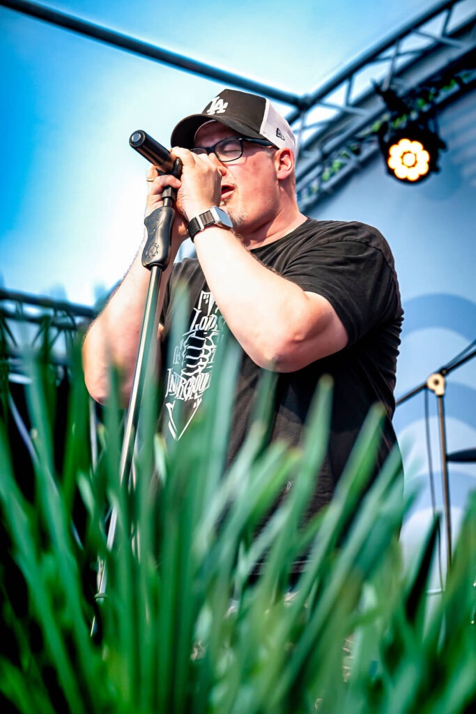Sänger mit Kappe am Mikrofon auf der Bühne