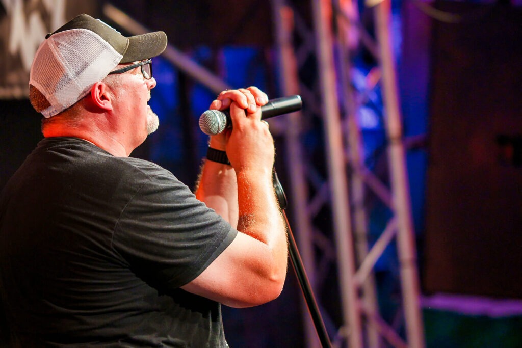 Mann singt auf Bühne mit Mikrofon