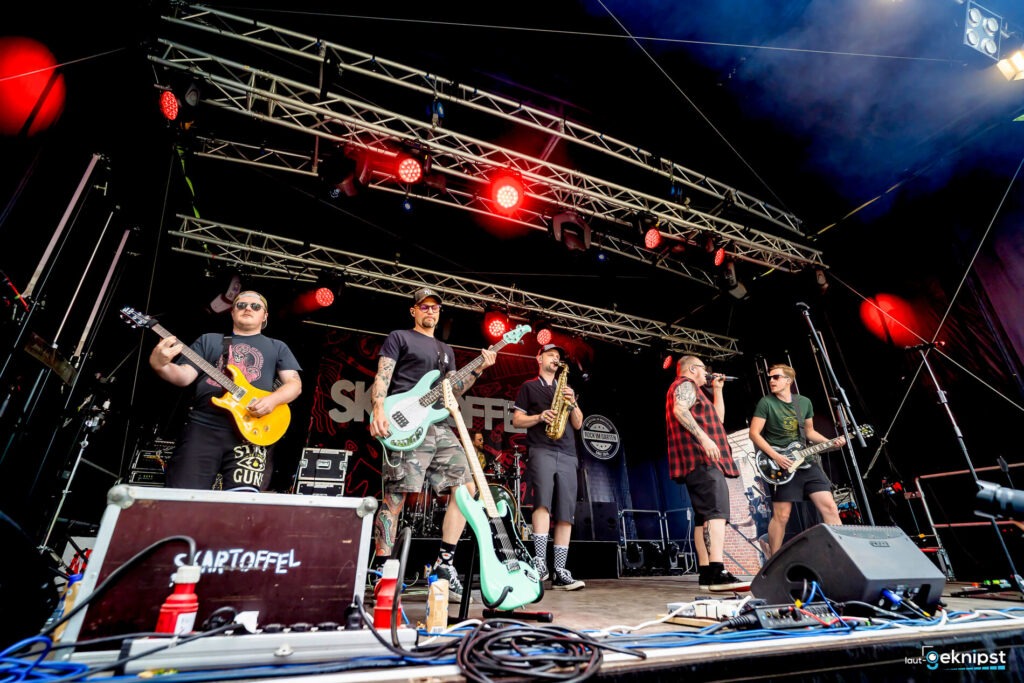 Band spielt auf einer Bühne mit Instrumenten.
