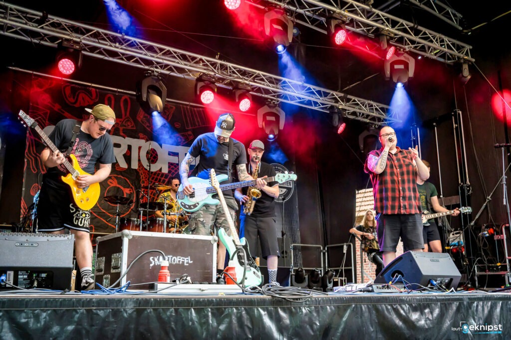 Band spielt live auf Bühne mit Instrumenten.