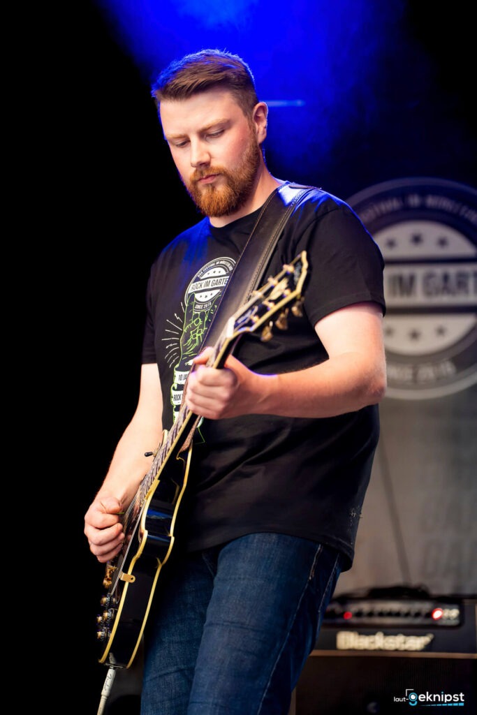 Mann spielt Gitarre auf Bühne