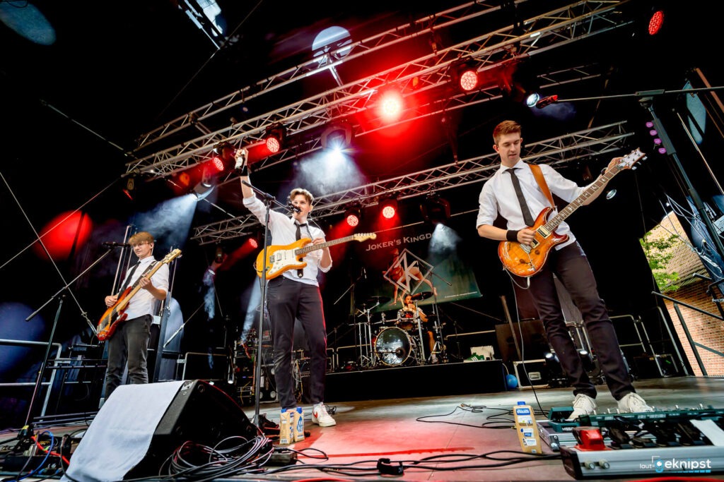 Band spielt live auf einer Bühne mit Instrumenten.