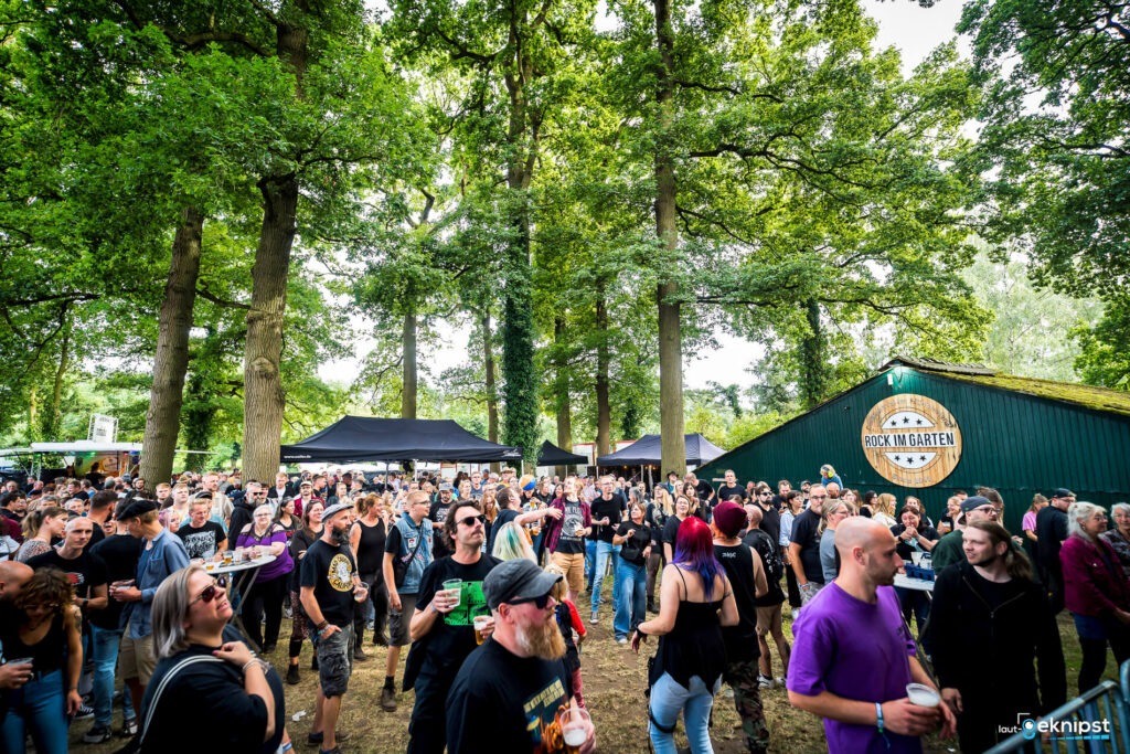 Menschenmenge auf Festival im Grünen mit Bühne.