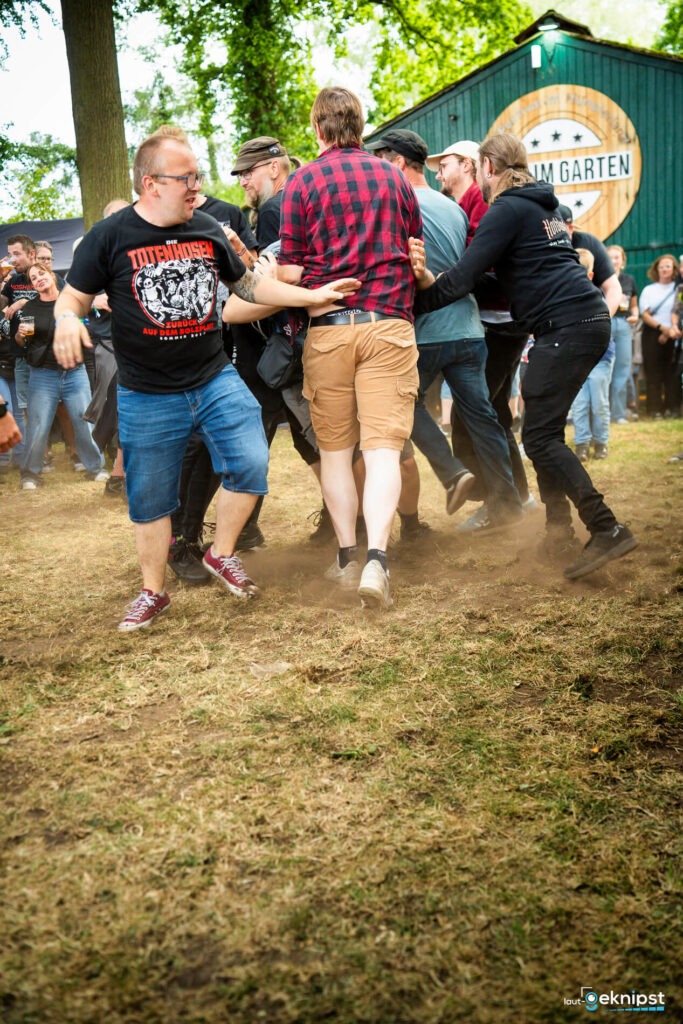 Menschen beim Konzert tanzen auf Wiese.