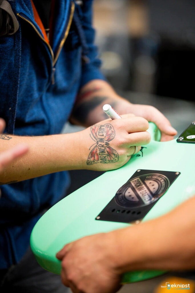 Person signiert mintgrüne Gitarre mit Marker