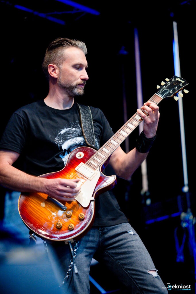 Mann spielt Gitarre auf einer Bühne.