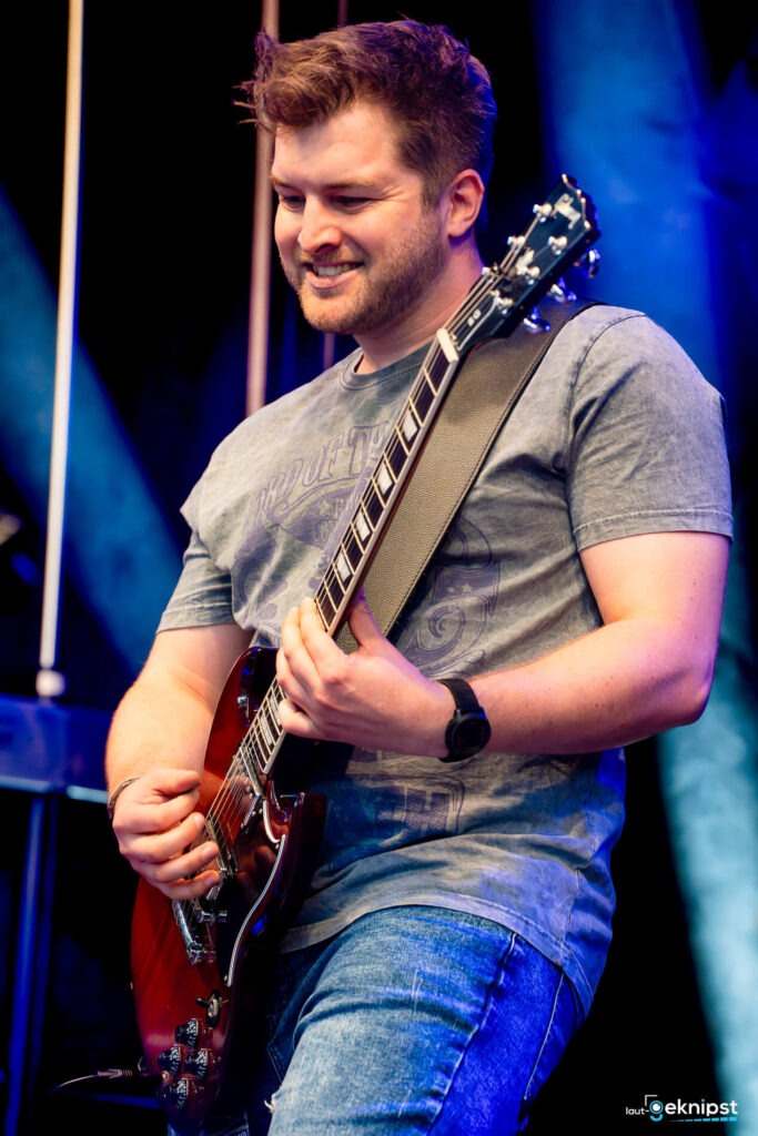 Gitarrist auf der Bühne mit E-Gitarre spielend.