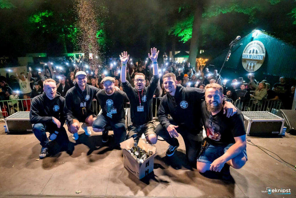 Gruppe von Männern auf einer Bühne bei Nacht