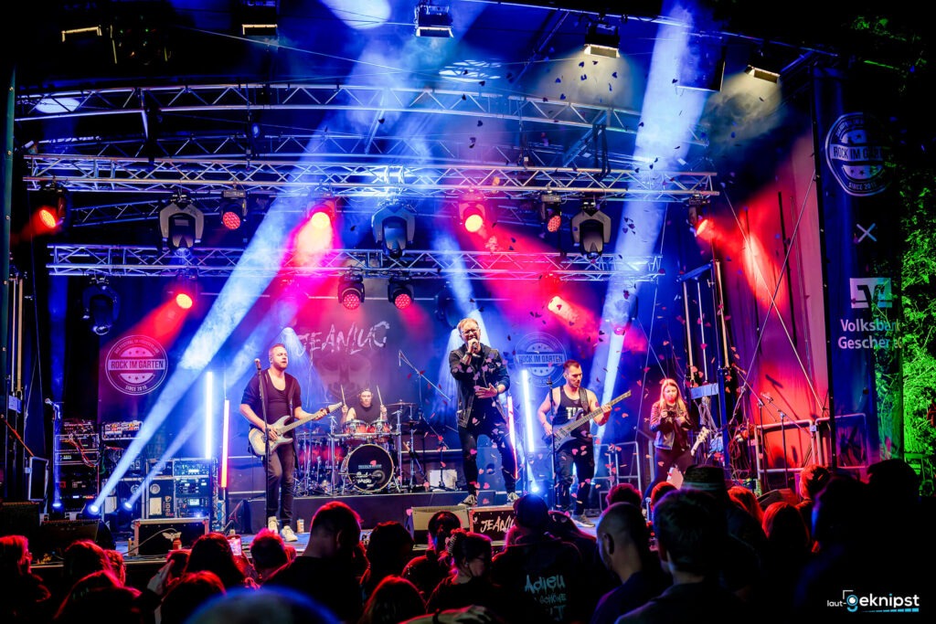 Rockband auf der Bühne mit Lichteffekten und Publikum.