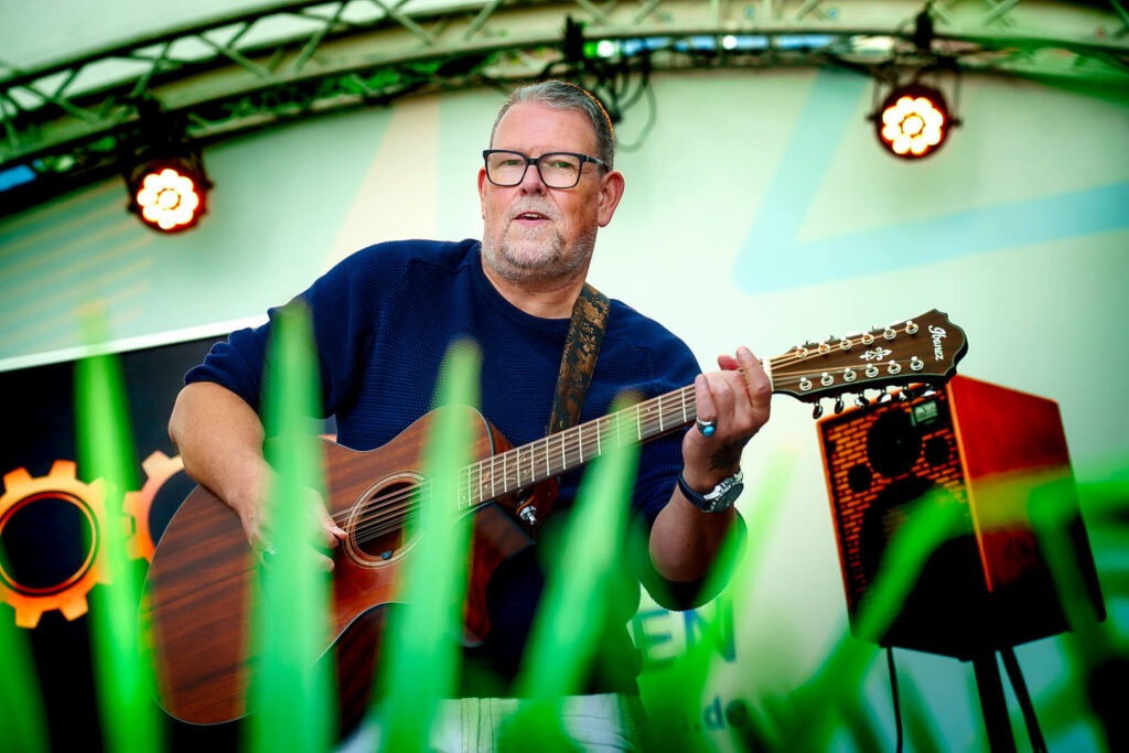 Mann spielt Akustikgitarre auf Bühne.