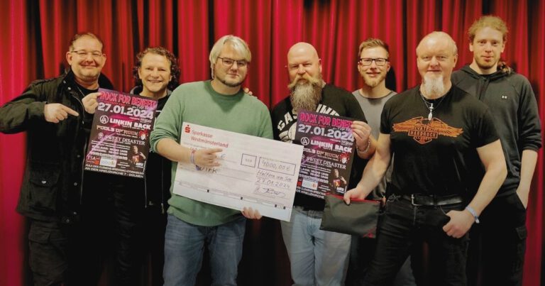 Gruppenfoto mit Scheck und Konzertplakaten vor rotem Vorhang.
