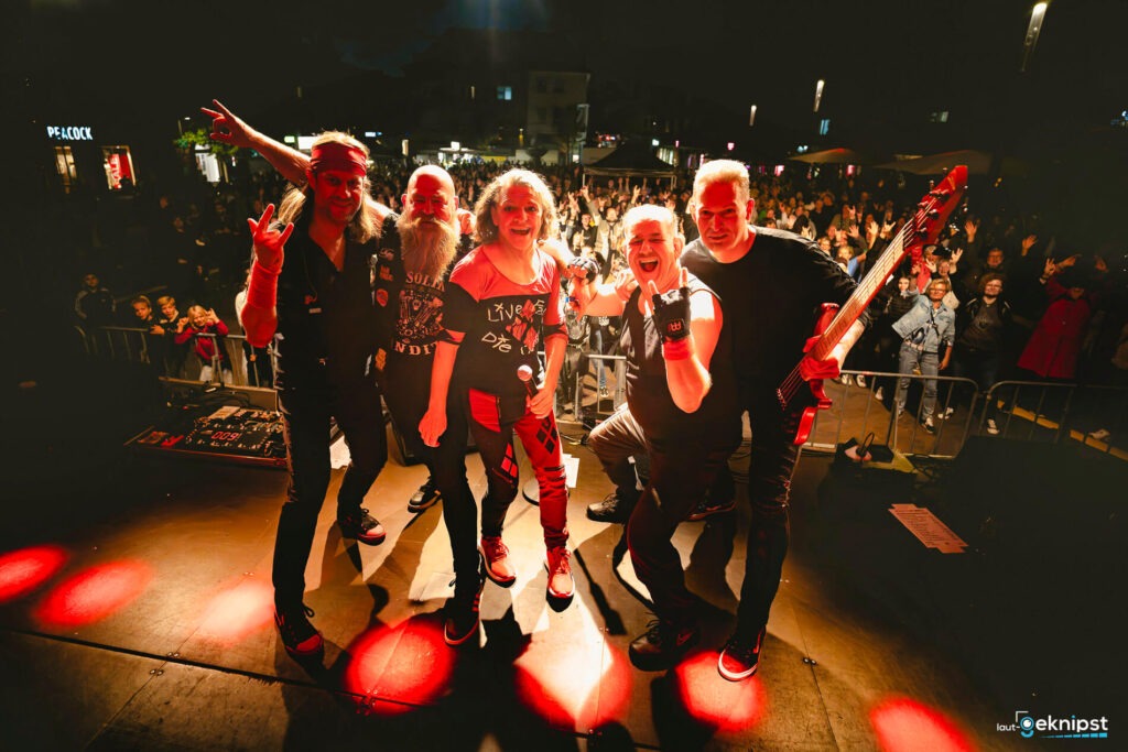 Band auf Bühne vor jubelndem Publikum