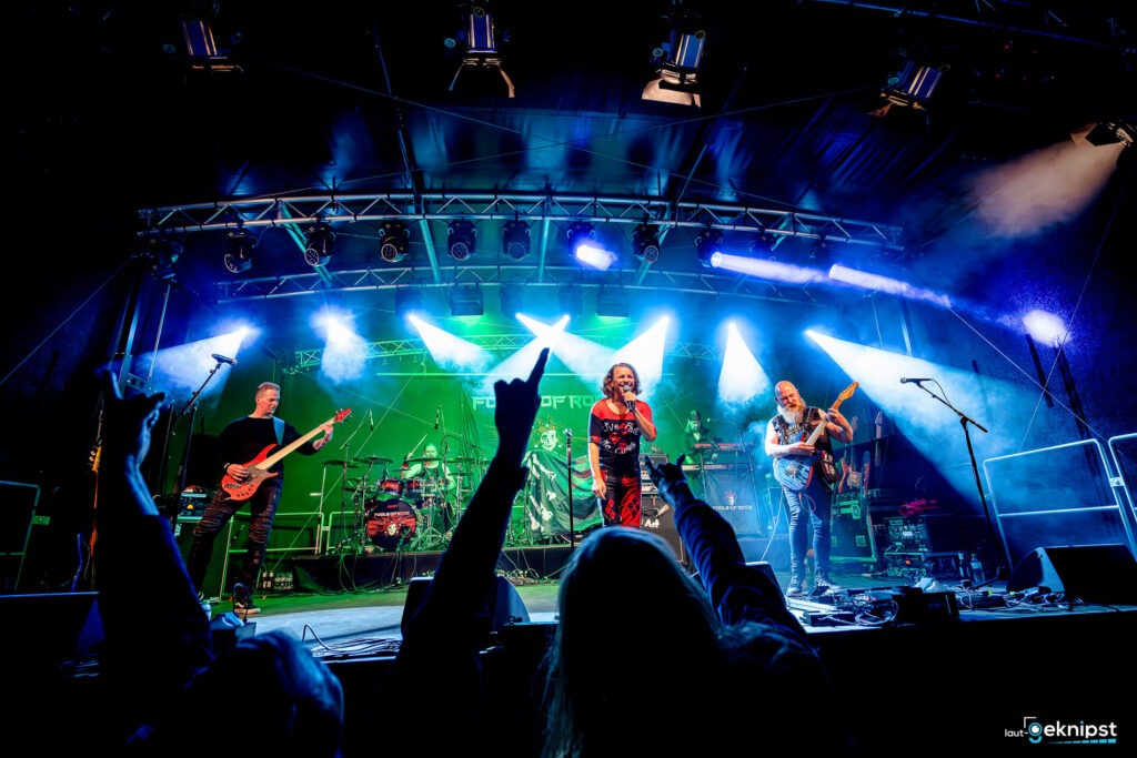 Rockband auf Bühne, Publikum jubelt.