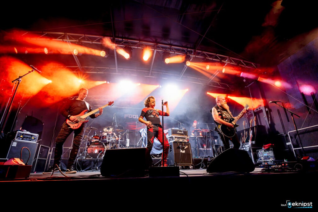 Liveband auf Bühne mit Lichteffekten und Instrumenten.