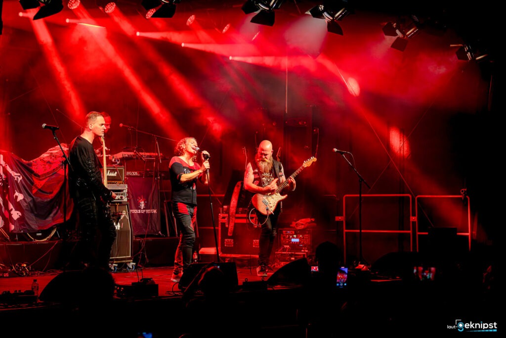 Rockband spielt auf beleuchteter Bühne.