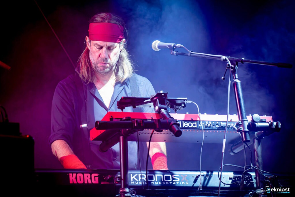 Mann spielt Keyboard auf der Bühne, intensives Licht.