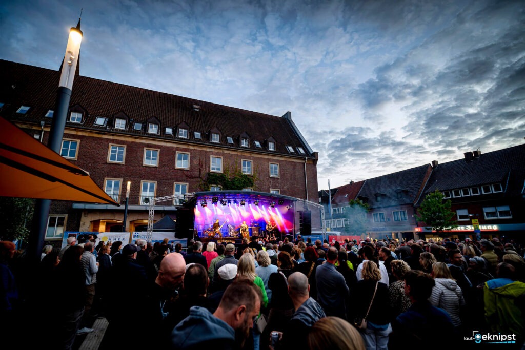 Open-Air-Konzert vor historischem Gebäude bei Abenddämmerung.