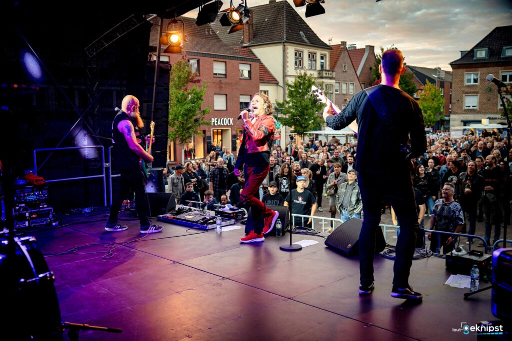 Band spielt auf einer Open-Air-Bühne vor Publikum.