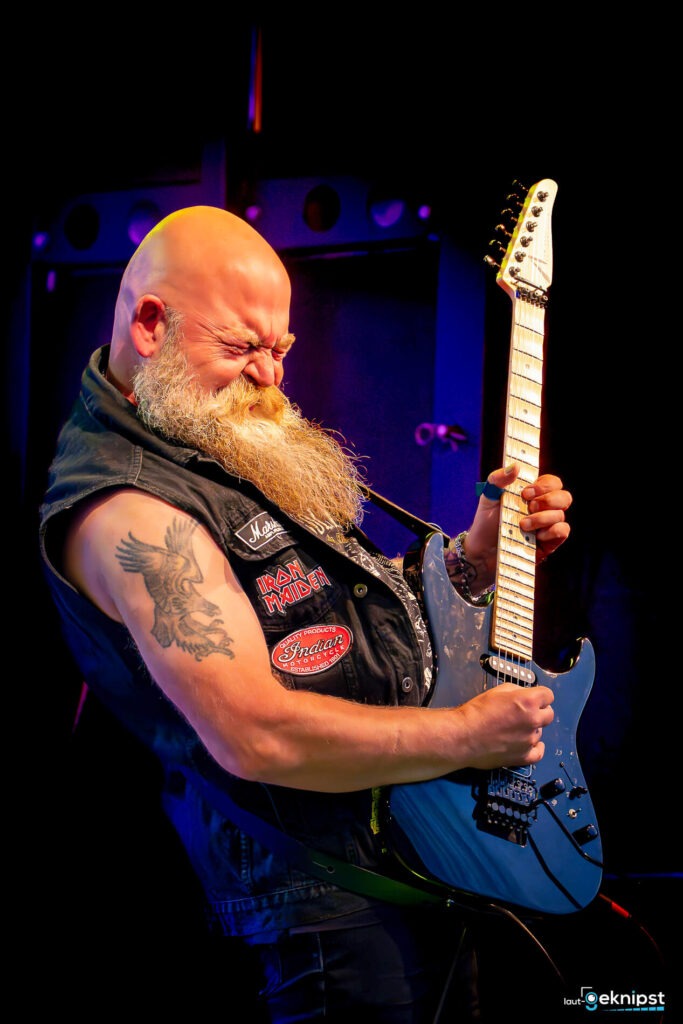 Gitarrist rockt auf der Bühne mit E-Gitarre.