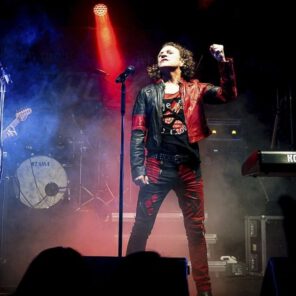 Band spielt Live-Konzert auf Bühne mit Lichteffekten.