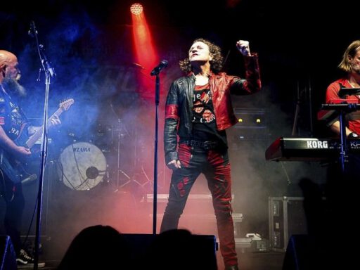 Band spielt Live-Konzert auf Bühne mit Lichteffekten.