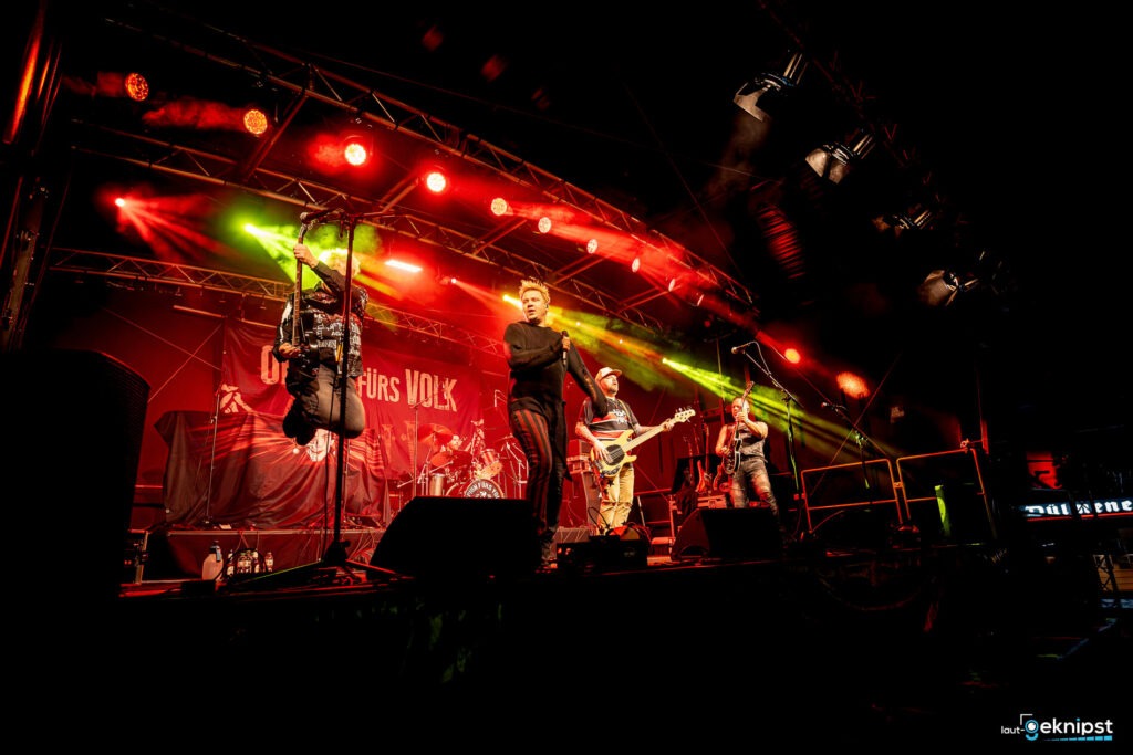 Rockband auf der Bühne mit Lichteffekten.