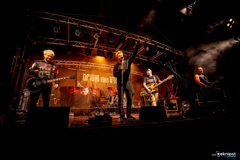 Band spielt auf beleuchteter Bühne im Konzert.