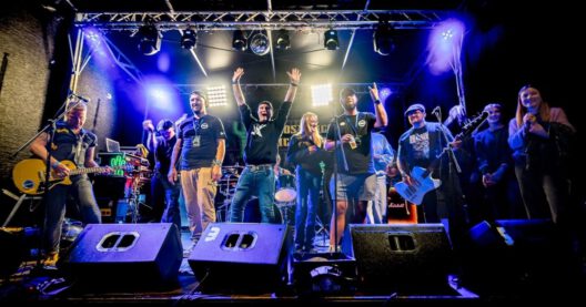 Bandmitglieder auf Bühne mit Instrumenten und Lichtshow.