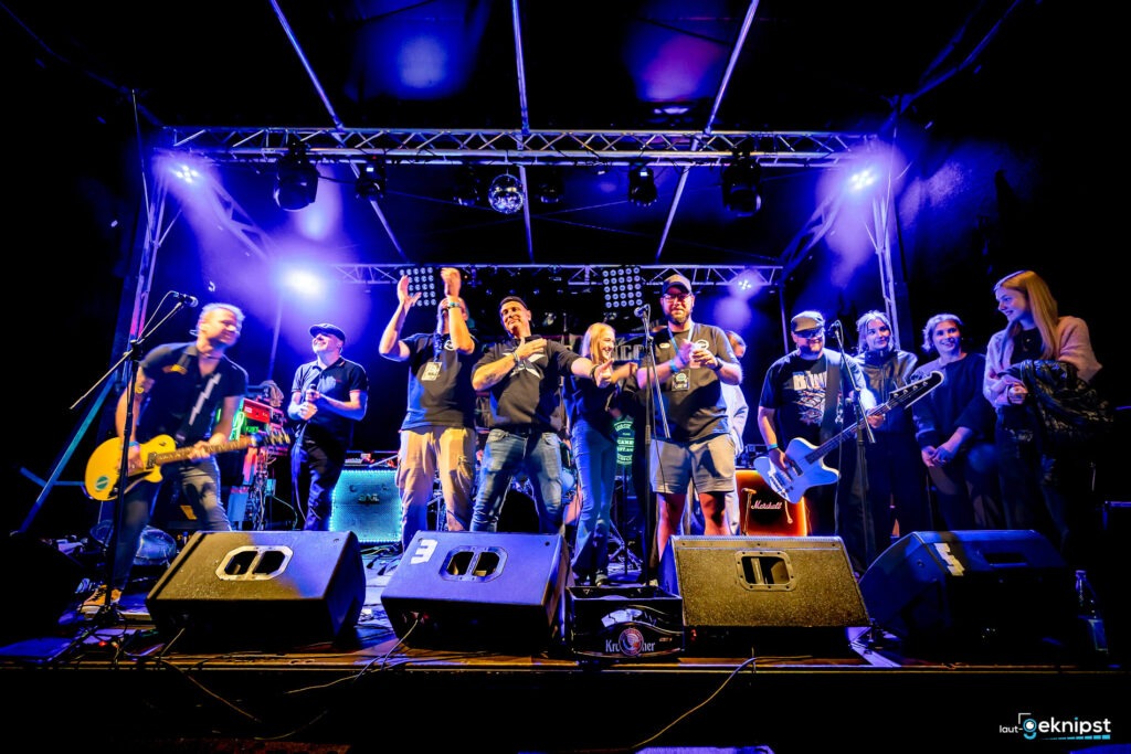 Band spielt live auf der Bühne, Publikum applaudiert.