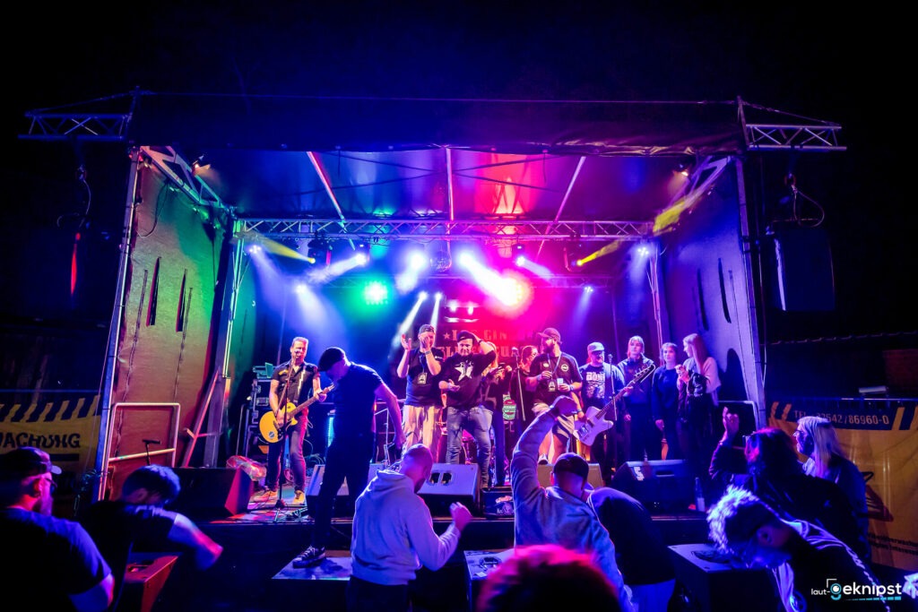 Konzertbühne mit Band und tanzendem Publikum bei Nacht