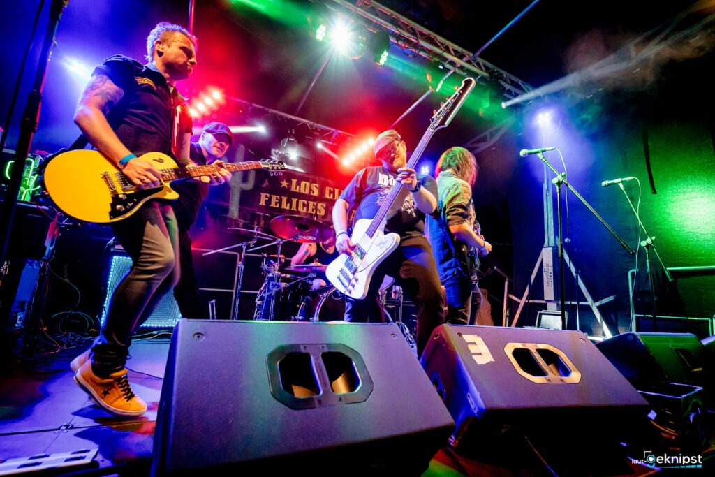 Band spielt Rockmusik auf Bühne mit bunten Lichtern.