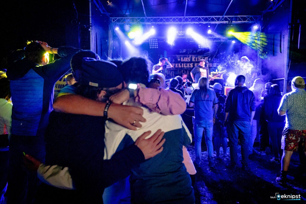 Menschenmenge genießt Konzert unter buntem Bühnenlicht.