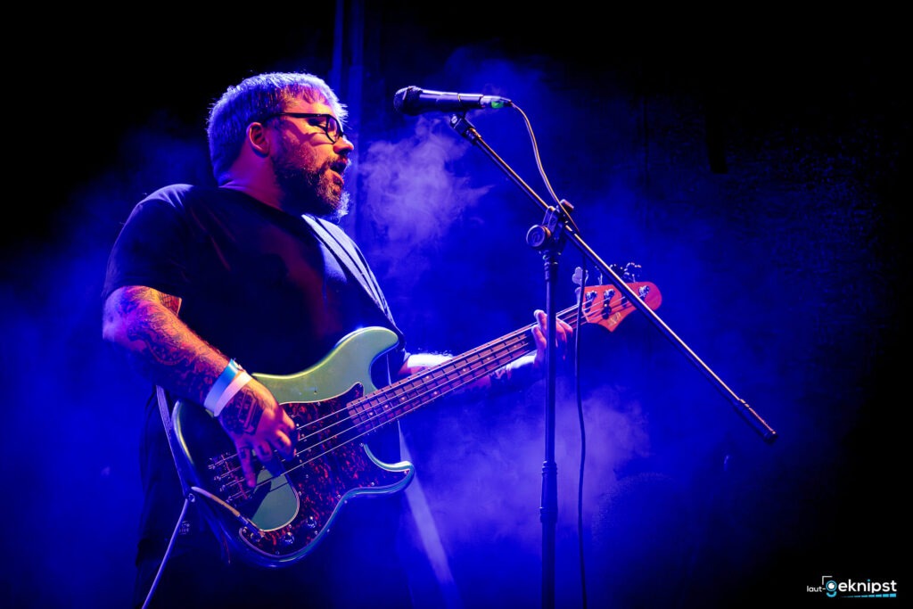 Musiker spielt E-Bass auf der Bühne.