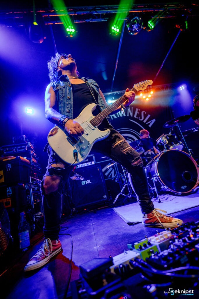 Gitarrist spielt Rockmusik auf Bühne mit buntem Licht.