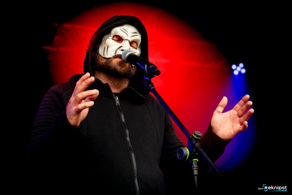 Mann mit Maske singt auf Bühne