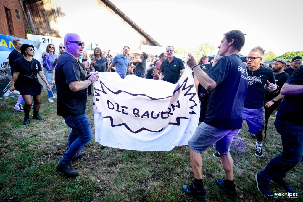 Menschen tanzen mit einem Banner auf einer Wiese.