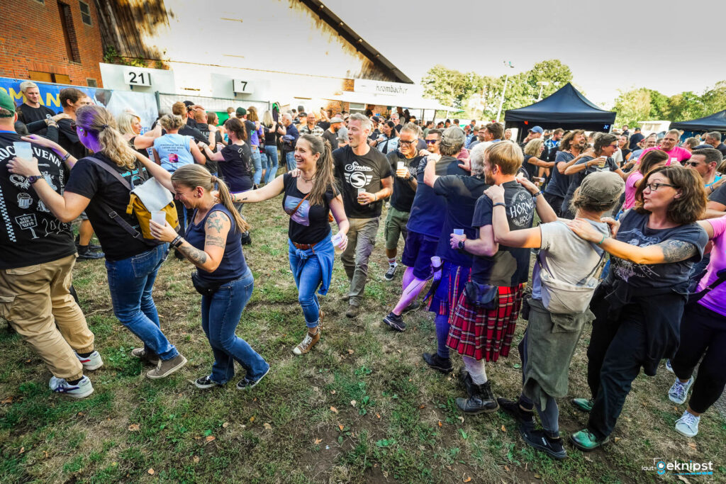 Menschen tanzen in einer Kette bei einem Festival.