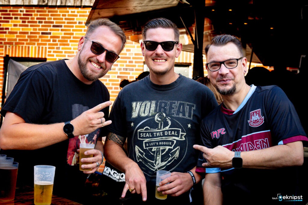 Drei Männer mit Getränken auf einem Festival