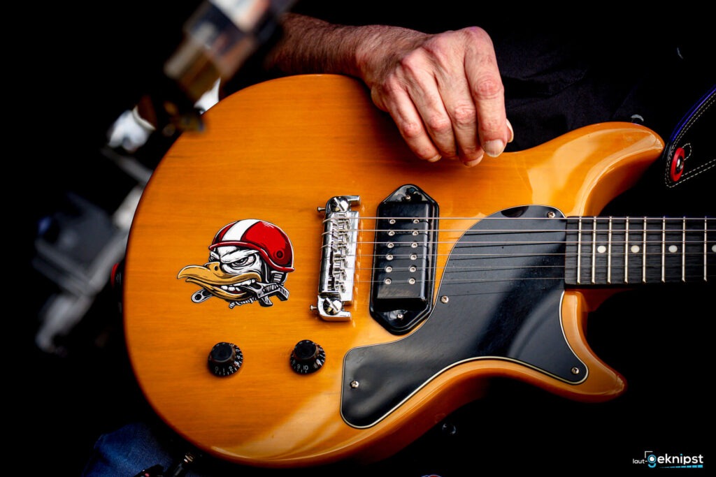 Gelbe E-Gitarre mit Cartoon-Aufkleber und Hand