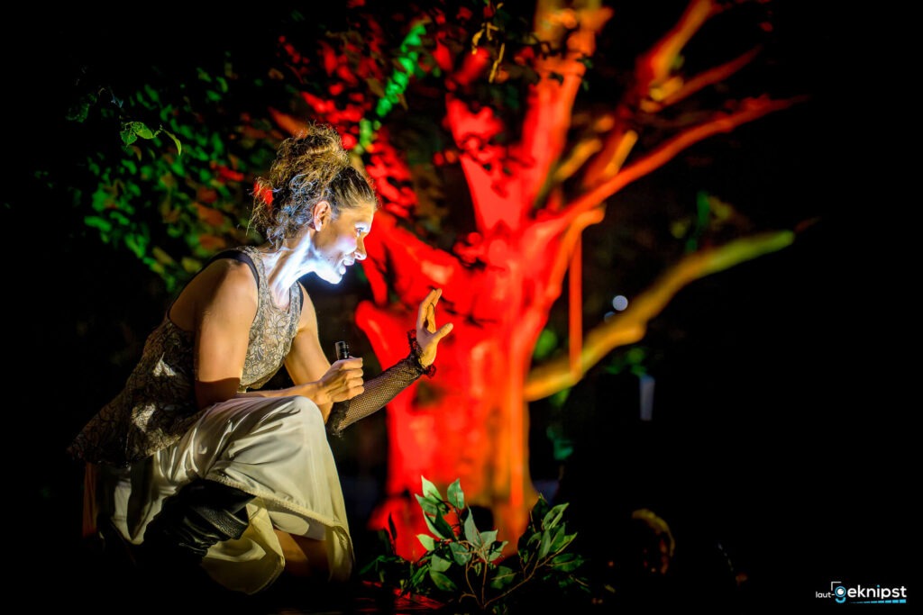 Frau spielt im bunten Licht vor Baum.