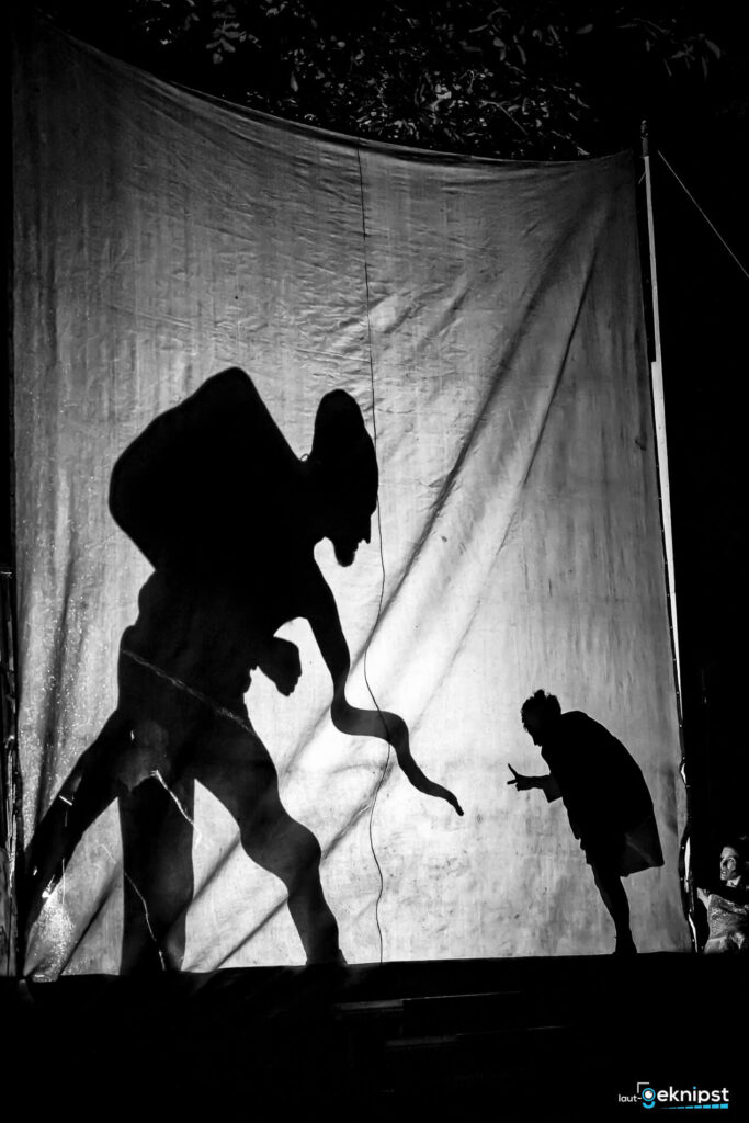 Silhouetten von Figuren auf einem beleuchteten Vorhang.