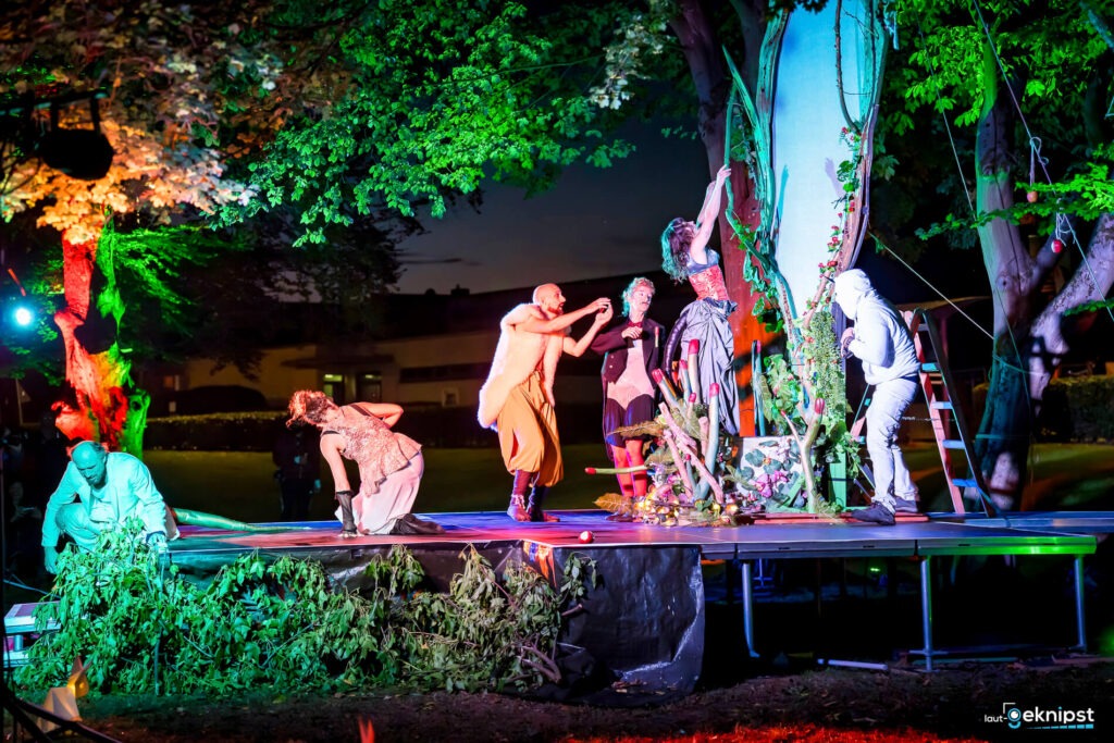 Bunte Theaterperformance im Freien mit mehreren Darstellern.