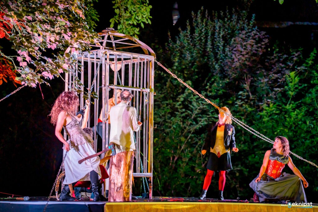 Theateraufführung mit Käfig und Darstellern im Freien