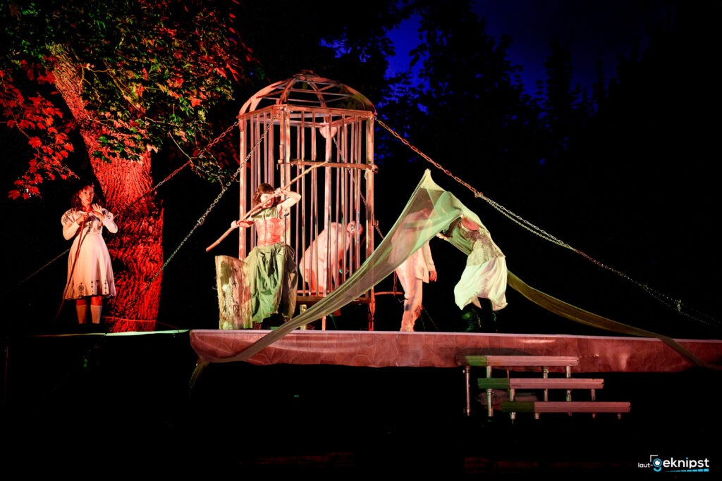 Theaterszene mit Käfig und Darstellern im Freien