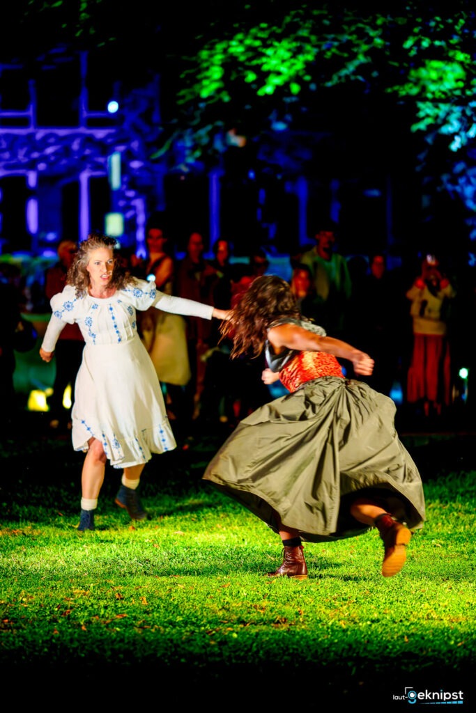 Zwei Frauen tanzen im Freien bei Nacht