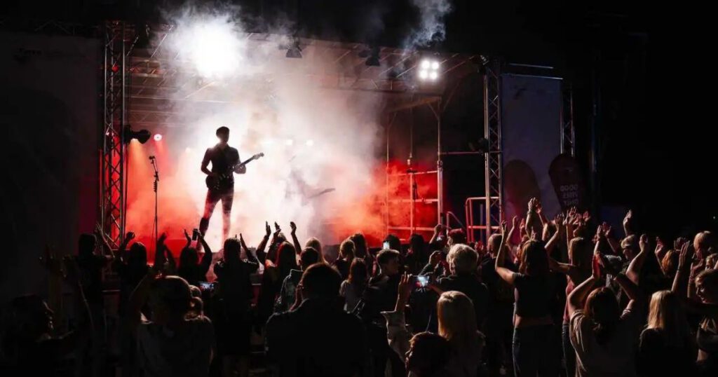 Konzert mit Gitarrist und jubelnder Menge im Nebel